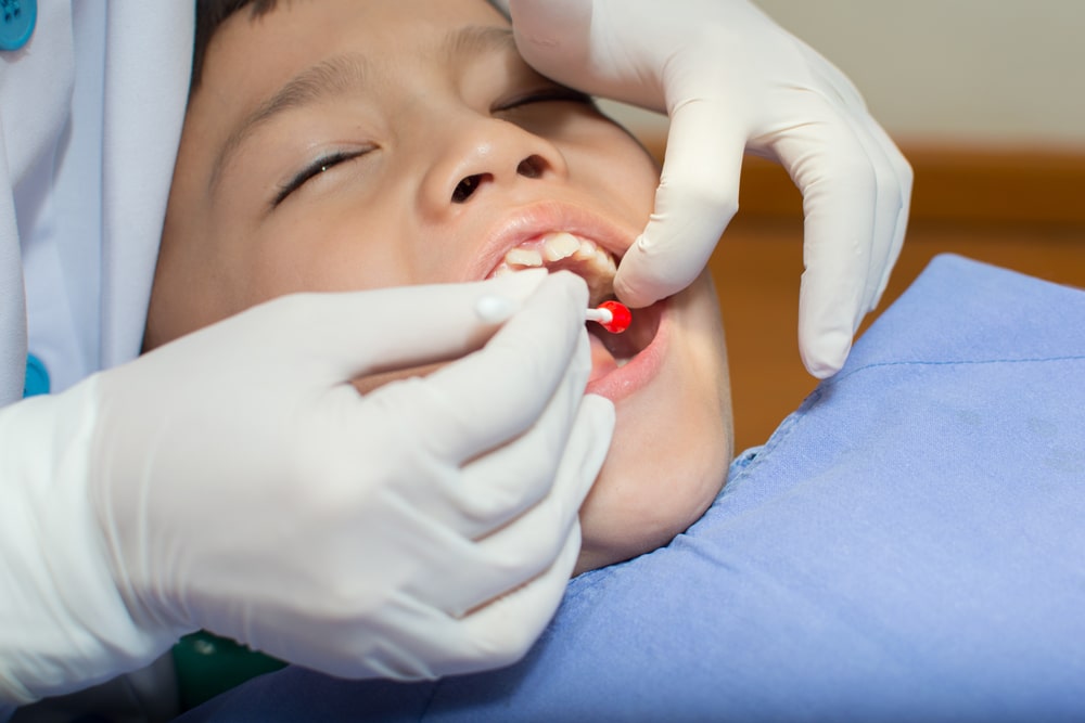 Pediatric dentist preparing a child for a tooth extraction