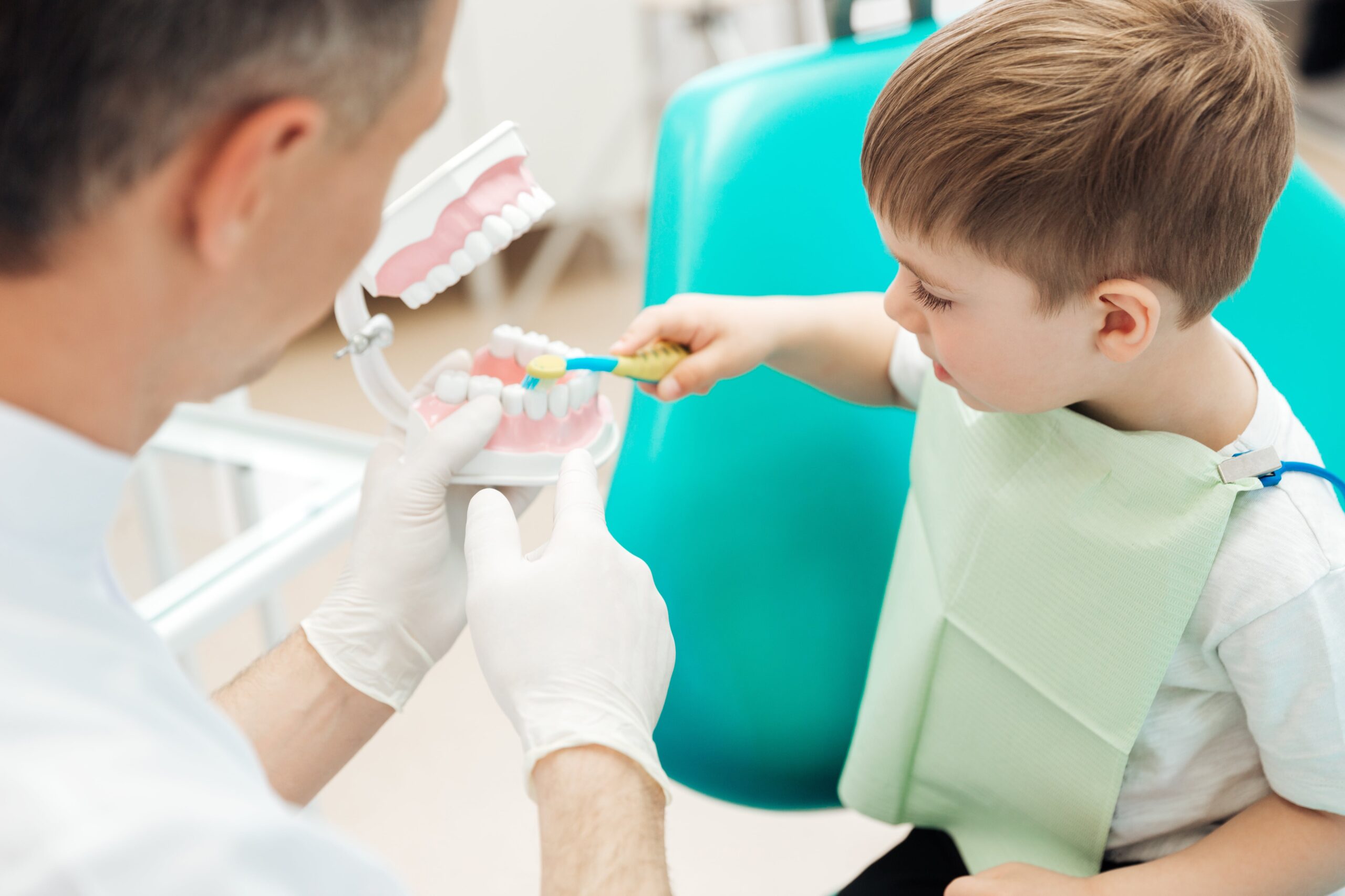 Pediatric dentist teaching a child how to brush his teeth